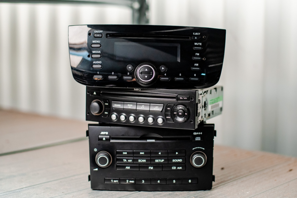 Three different car radios on a white shelve