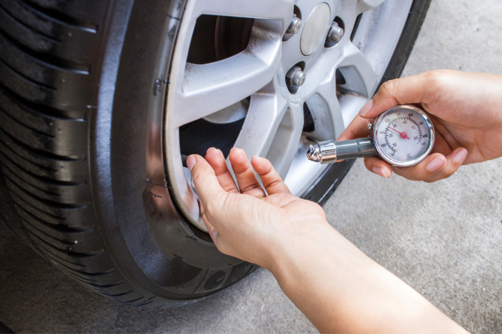 Close up de uma mão a medir a pressão de um pneu do carro