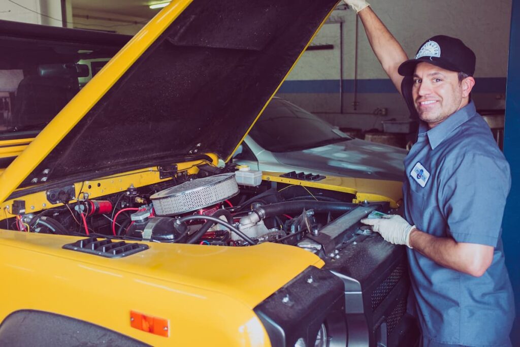 Un mécanicien ouvre le capot d'une voiture pour changer l'huile du moteur